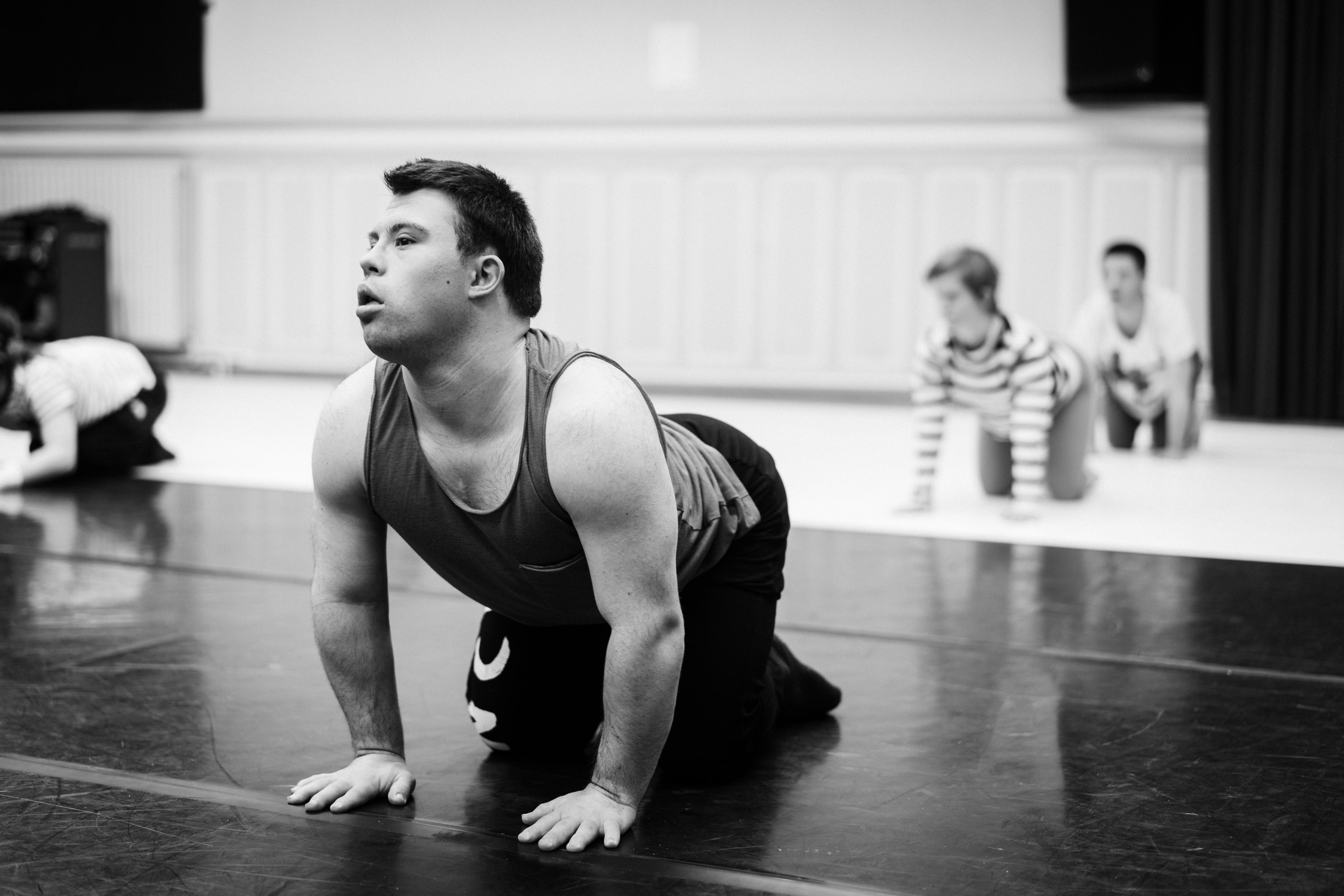 Four people in a dance studio. They are doing the cow pose.