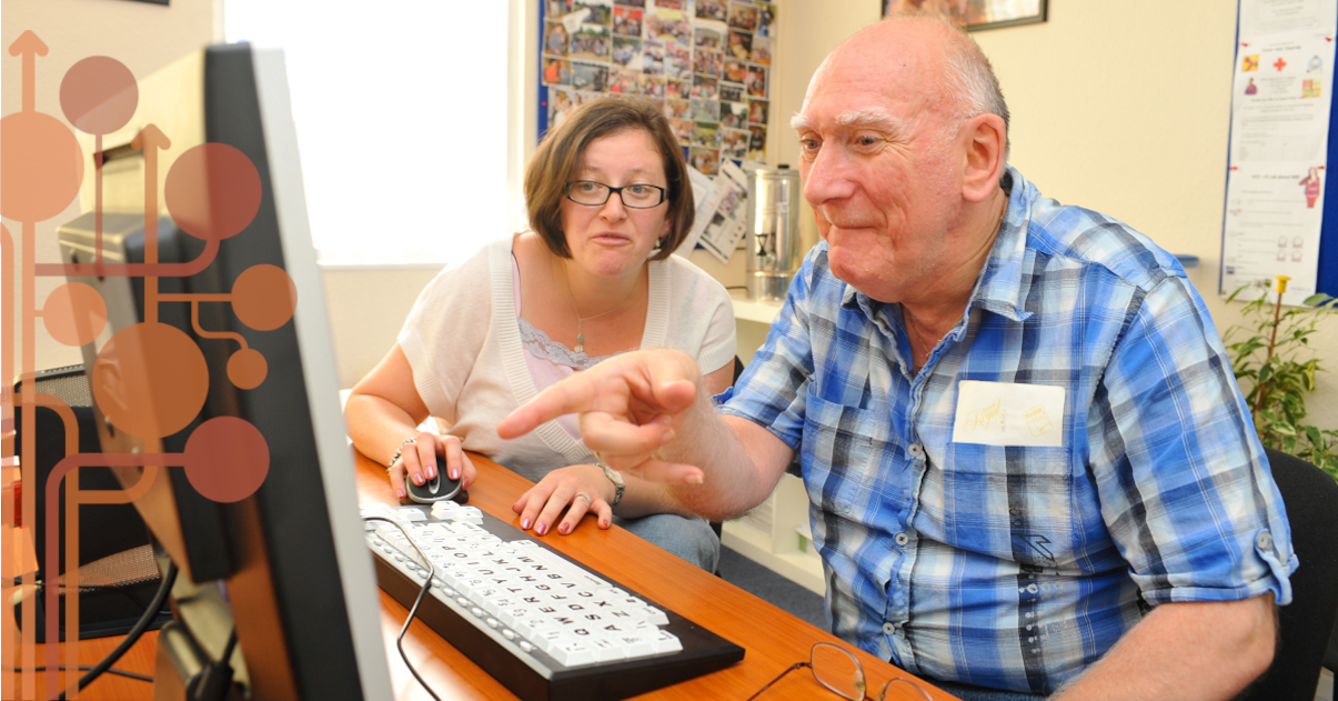 Kobieta w średnim wieku pomaga starszemu mężczyźnie obsługiwać komputer.