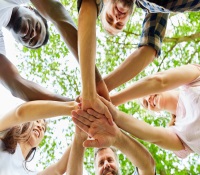 Different races placing hands on top of each other and demonstrating good social integration