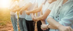 Line of workers joining hands to create a link.