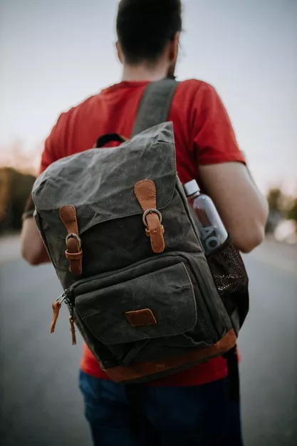 Enfoque-selectivo-disparo-hombre-pie-carretera-mochila-solapa-botella-agua_181624-27329