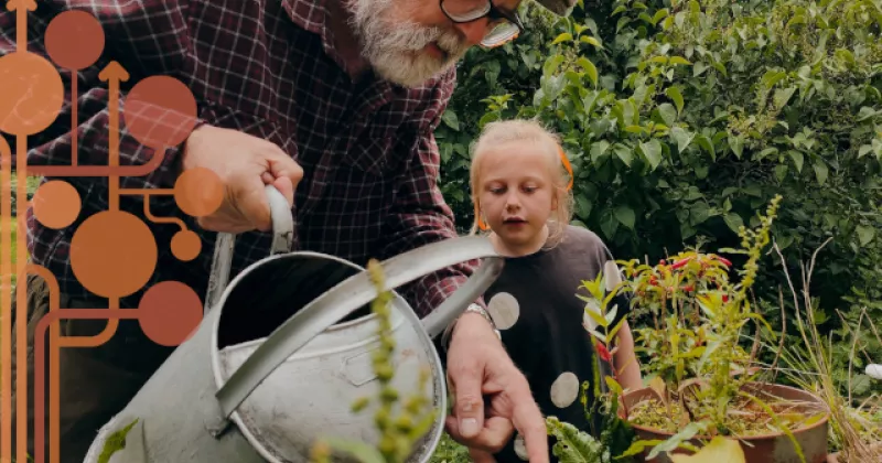 starszy mężczyzna pokazuje dziewczynce jak dbać o rośliny.