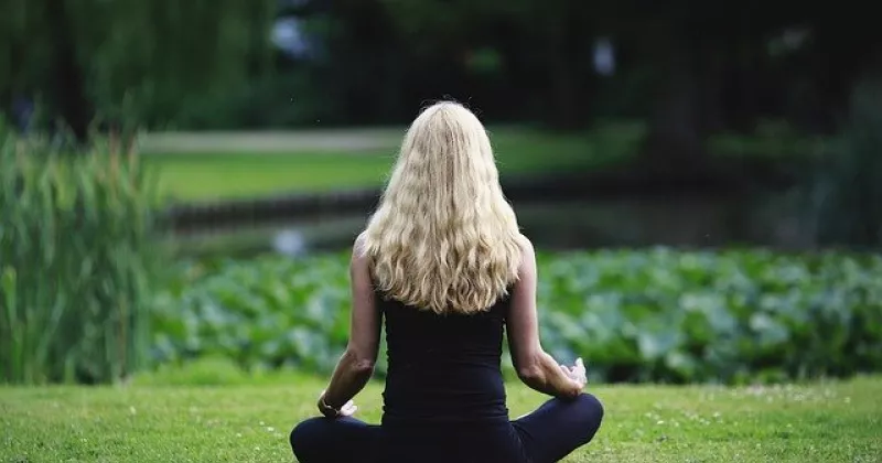 Woman meditating on a lawn.